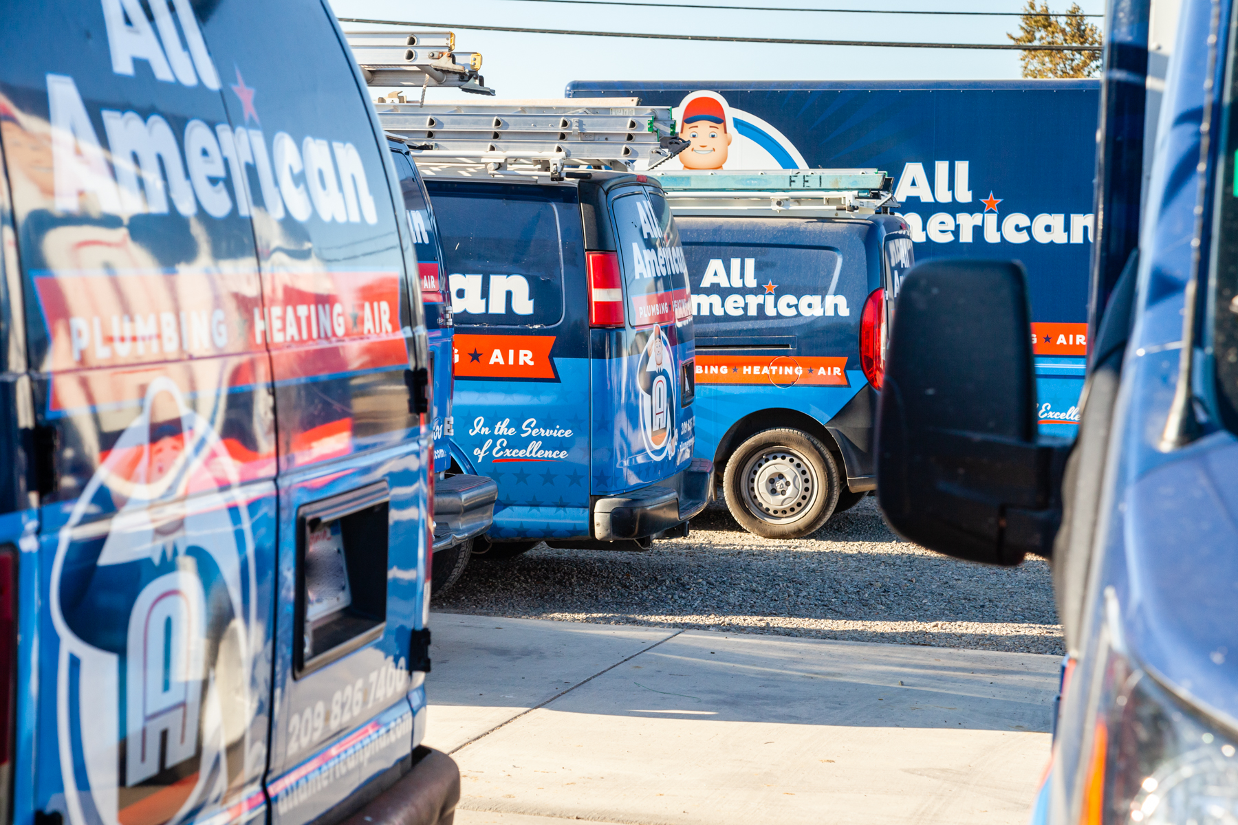 All American Plumbing Heating & Air service vans lined up at the shop